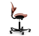 Ergonomic HAG Capisco Puls 8020 saddle chair in rosehip color with silver aluminium base and adjustable gas lift.